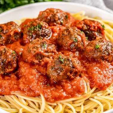 Close up view of baked meatballs on top of spaghetti.