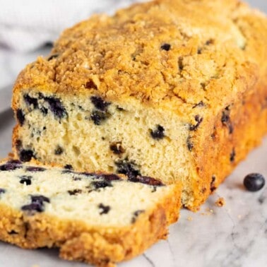 Loaf of Blueberry Pancake Bread on a marble slab with the end sliced to reveal a cross-section of blueberries inside.