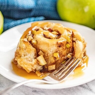 A caramel apple cinnamon roll served on a white plate