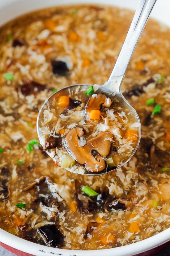 Restaurant style chicken hot and sour soup is super easy to make and takes all of 30 minutes from start to finish! It's got that perfect hot and sour flavor that everyone loves. A ladle of Chicken Hot and Sour Soup with mushroom, carrot, celery and tofu taken from a pot