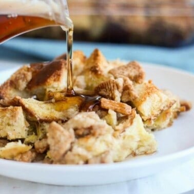 Cinnamon toast crunch breakfast casserole on a white plate getting syrup poured on it.