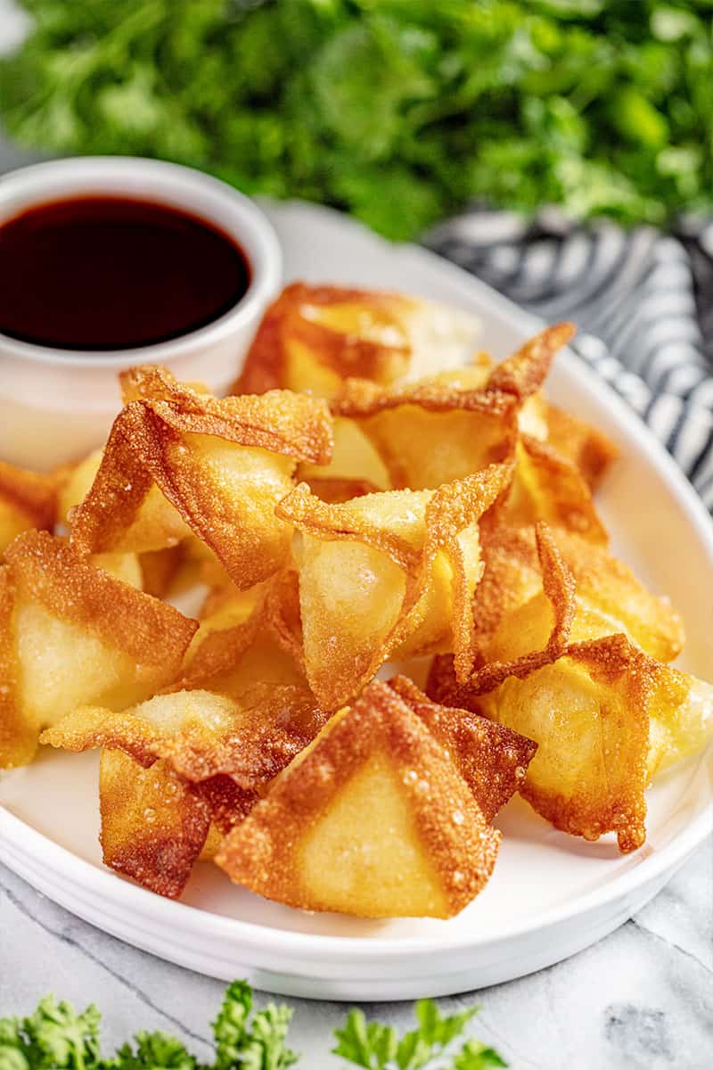 A platter of cream cheese wontons and sweet and sour sauce.