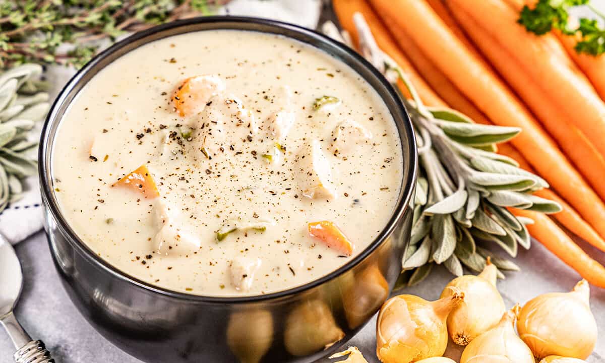 A black bowl filled with creamy chicken soup.