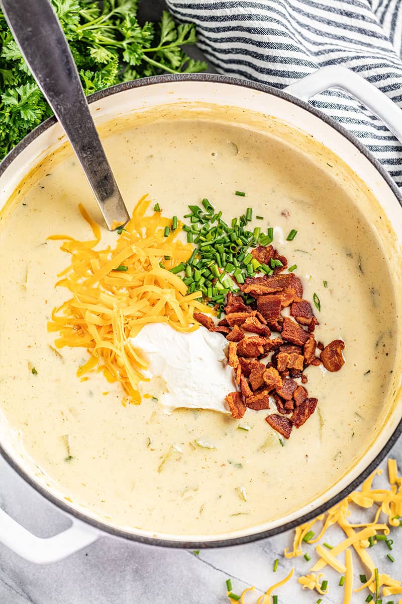 Potato soup in a large soup pot with a ladle inside.