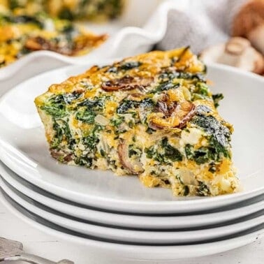 A piece of crustless spinach quiche on a stack of plates.