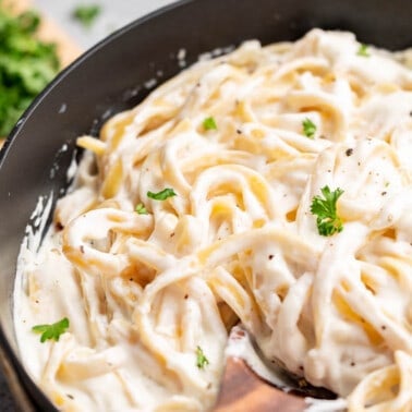 Close up view of fettuccine Alfredo in a saucepan.