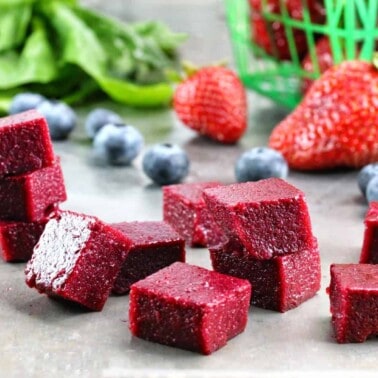 Cubes of Homemade Fruit and Vegetable Snacks stacked on a counter. These snacks are packed with fresh blueberry, strawberries and spinach