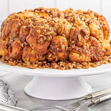 Gooey caramel pecan monkey bread on a white cake plate.