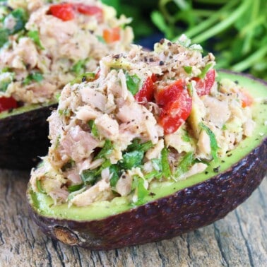 Two tuna stuffed avocados on a table top.