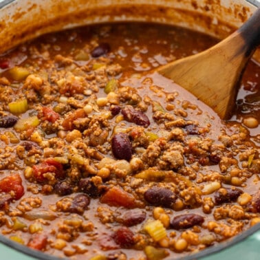 A large, mint green pot filled with turkey chili.