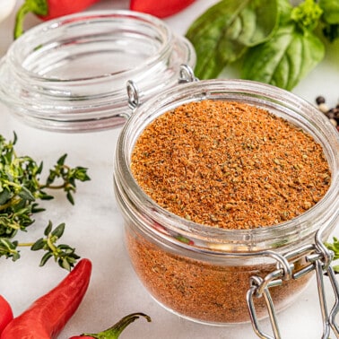 An open small glass jar filled with homemade cajun seasoning.