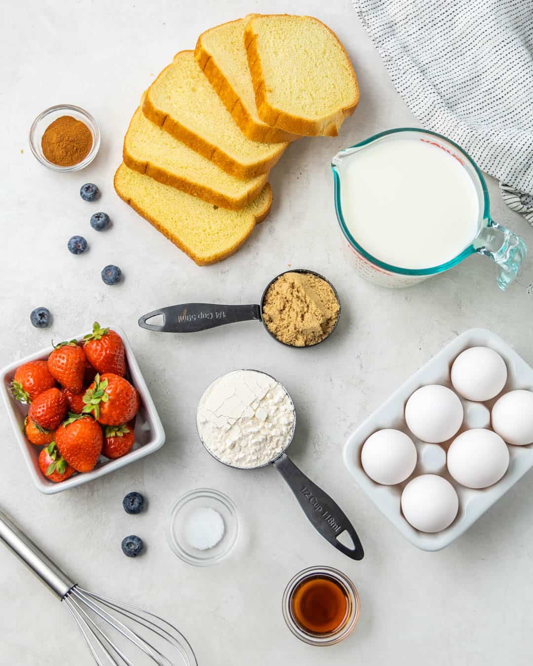 An overhead view of the raw ingredients needed to make French toast on a clean kitchen counter.