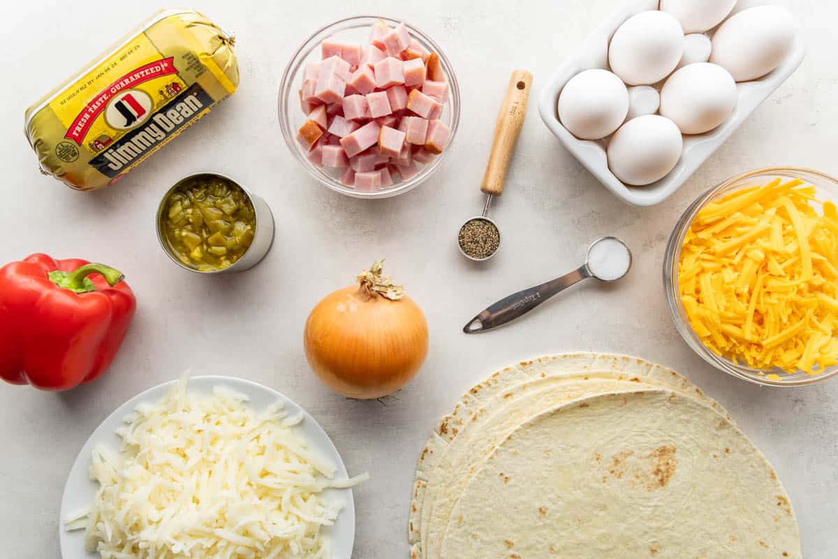 Overhead view of the raw ingredients needed to make breakfast burritos on a clean kitchen counter.