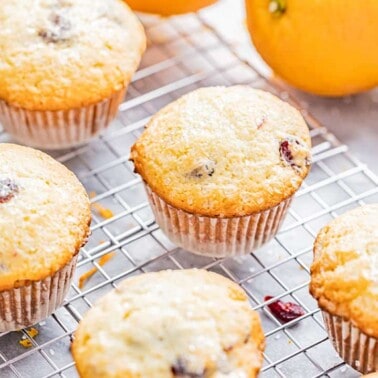 Orange cranberry muffins on a cooling rack.