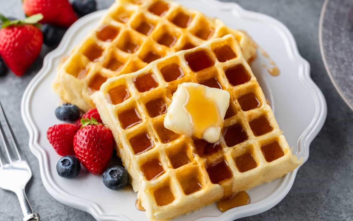 Homemade waffles on a white plate with berries.