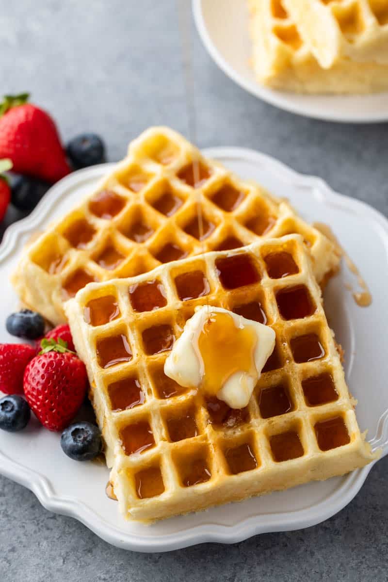 Overhead view of syrup drizzled on top of a stack of homemade waffles.