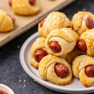 Pigs in a blanket stacked on a dinner plate.