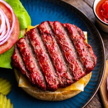 An overhead view of a smoked burger sitting atop a bun ready to be sandwiched into a burger.