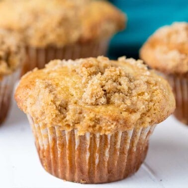 Close-up view of Sour Cream Coffee Cake Muffins on white painted wood table top.