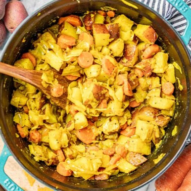 Bird's eye view of Tikel Gomen Potato and Cabbage Dish in a teal colored enameled cast iron dutch oven with a wooden spoon.